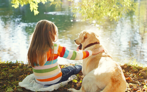 Menina com cachorro na frente de lago