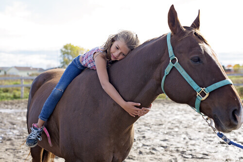 Equoterapia: menina abraçando cavalo