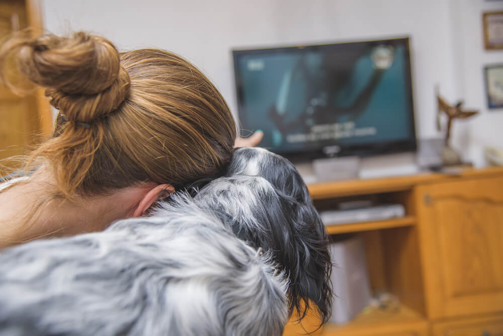 Dona com seu cão assistindo TV