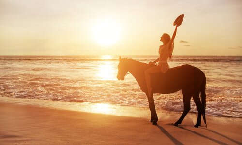 Mulher andando de cavalo na praia