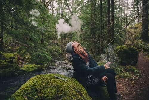 Mulher fumando em floresta